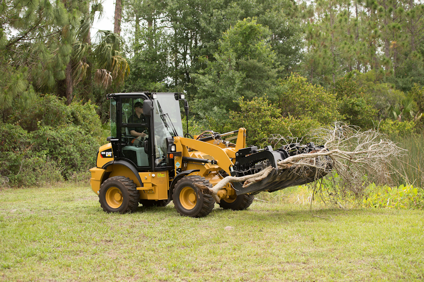 Caterpillar compact wheel loader with industrial grapple rake attachment
