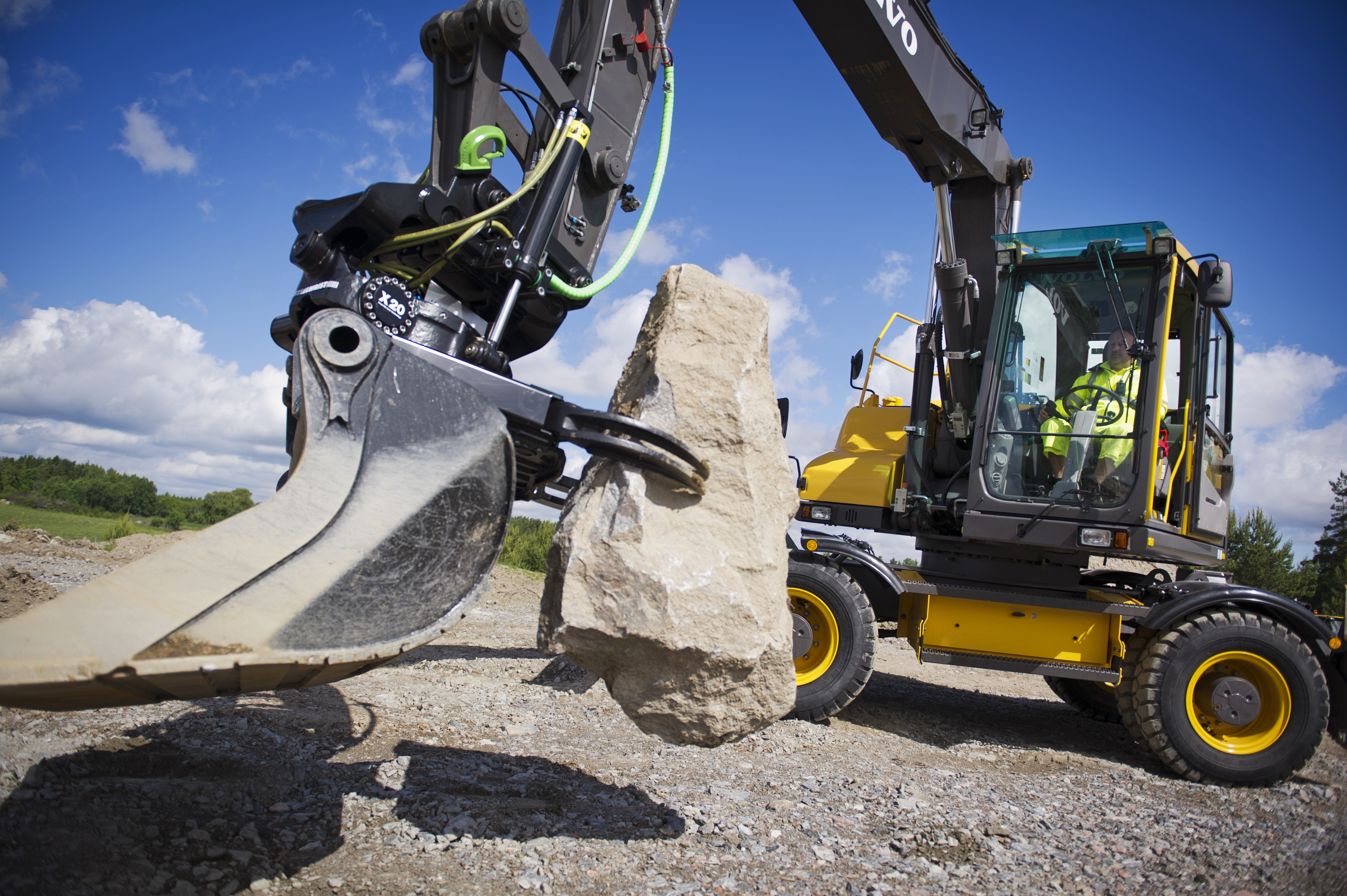 Volvo excavator with tiltrotator grasping a large rock