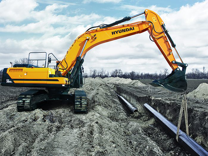 Hyundai excavator lowering a pipe into a trench
