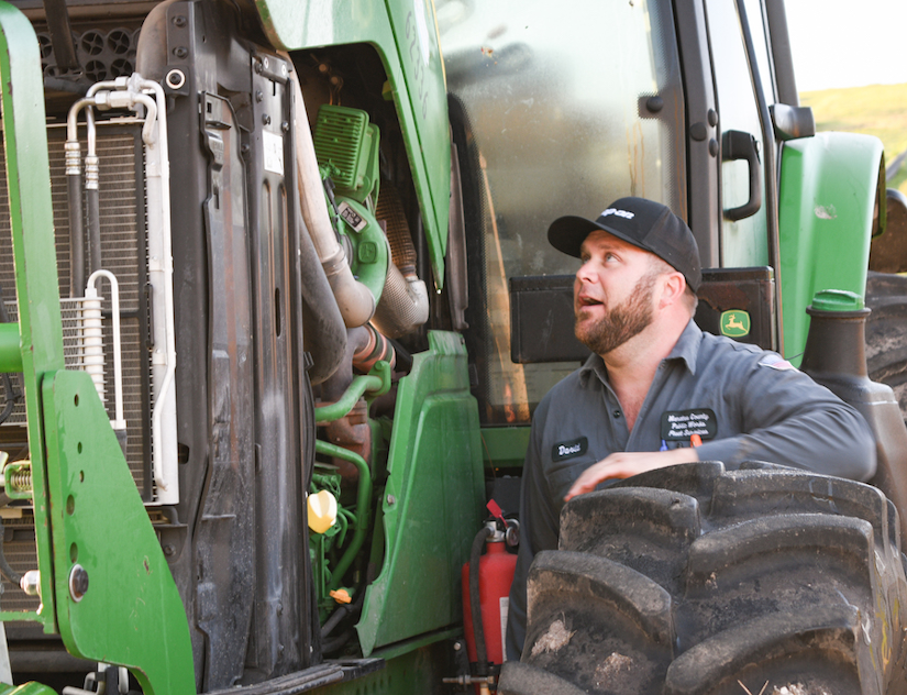 David Alligood checking the engine on a farm tractor